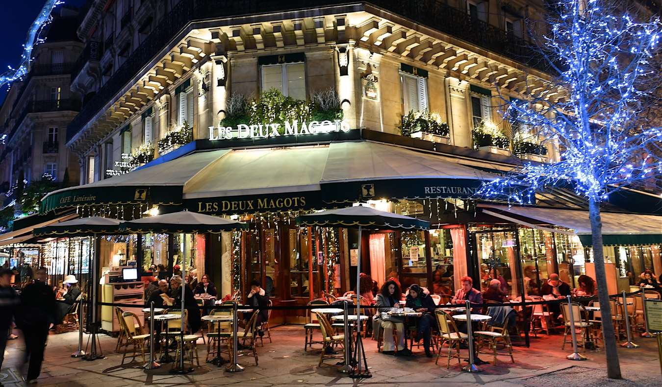 The outside of Le Deux Magots cafe lit up at night in Saint-Germain-des-Prés in Paris, France