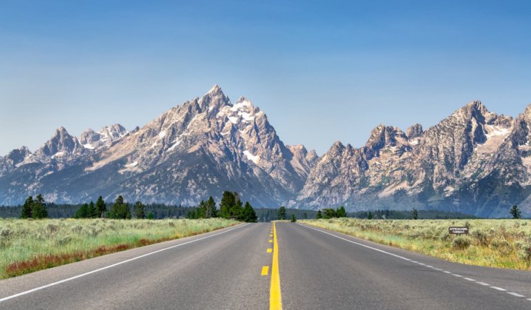 The open road on a sunny day in Wyoming, USA with mountains in the background