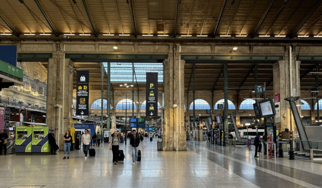 People rolling luggage through a train station in France