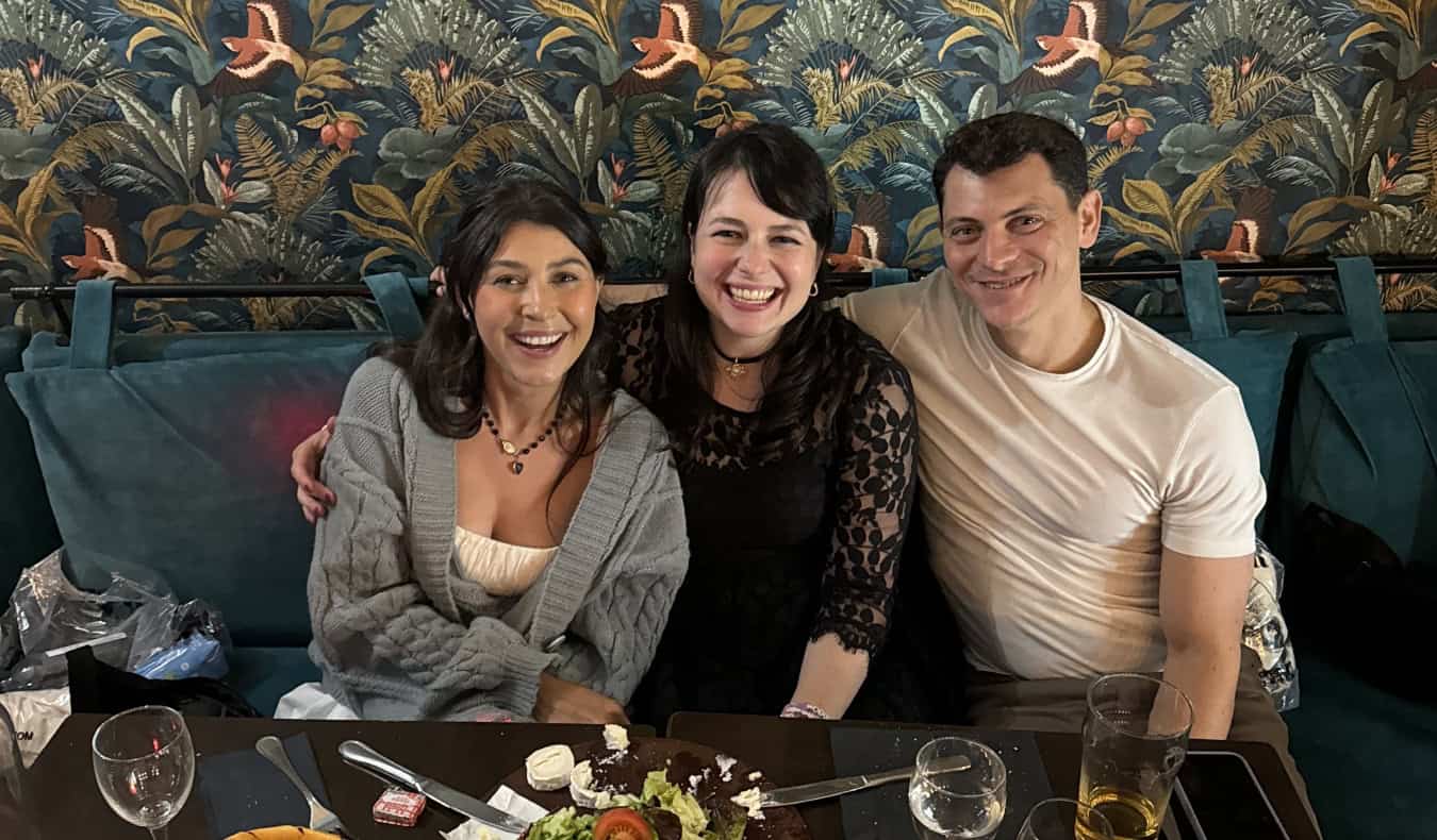 Nomadic Matt sitting with two female friends at a table having wine and cheese in Paris, France