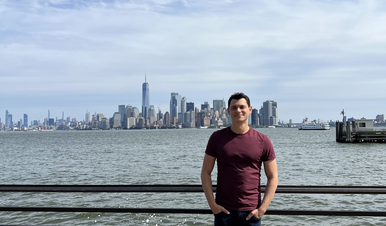 Nomadic Matt leaning on a railing with the Manhattan skyline behind him