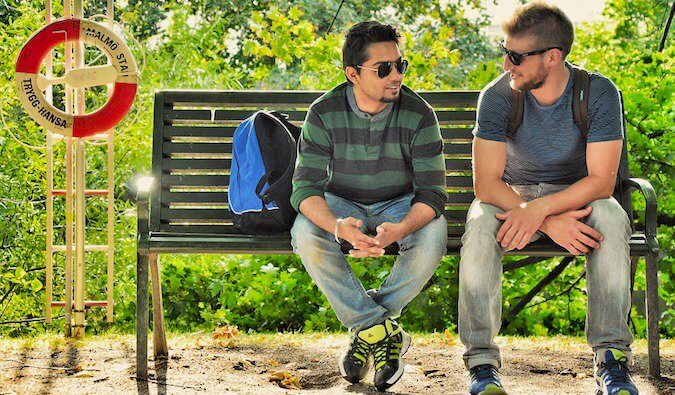 Two people talking on a bus stop bench