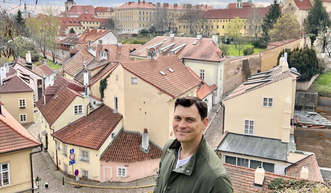 Nomadic Matt posing for a photo near old buildings in Prague, Czechia