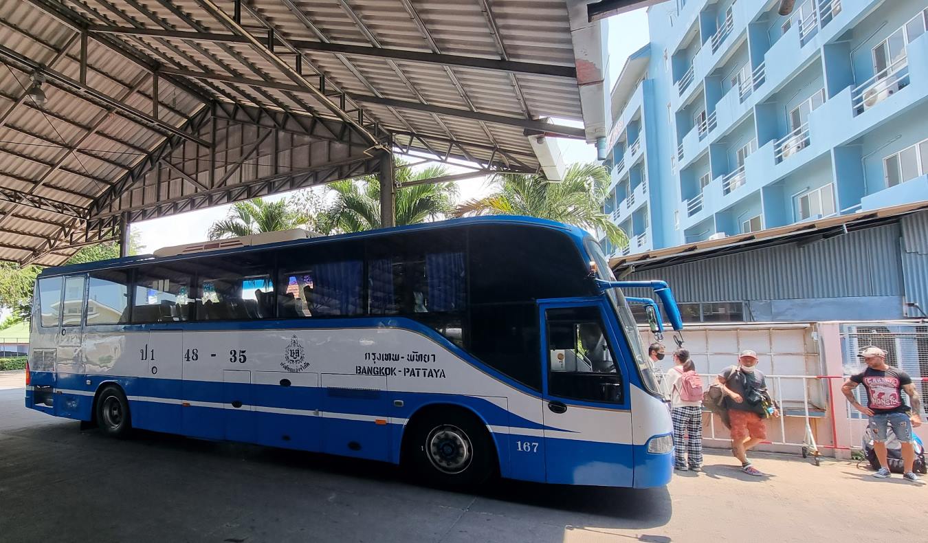 People lined up outside a blue and white coach bus at Pattaya bus terminal in Thailand