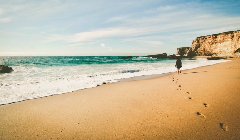 A solo female traveler walking alone on a sandy beach